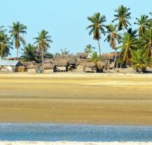 Tradycyjna wioska na Madagaskarze otoczona palmami na piaszczystej plaży.