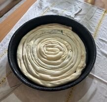 Surowe ciasto burek zawinięte w spiralę przed pieczeniem.