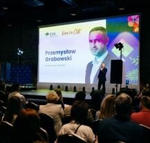 Przemysław Grabowski na scenie podczas oficjalnej części spotkania integracyjnego CUK 2025, przemawia do zgromadzonych pracowników.